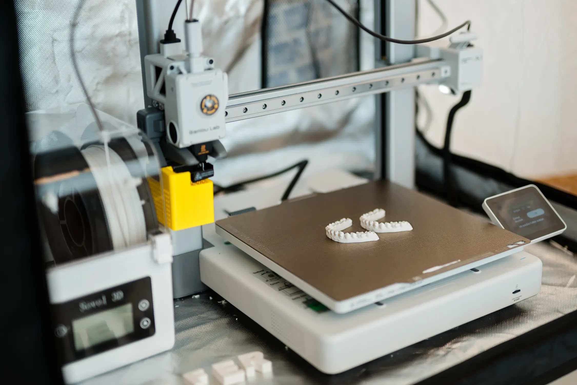 3D-Drucker im Praxislabor mit zwei frisch gedruckten Zahnmodellen auf der Druckplatte